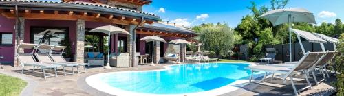 una piscina con sillas y sombrillas junto a una casa en Sweet Life Villas, en Peschiera del Garda