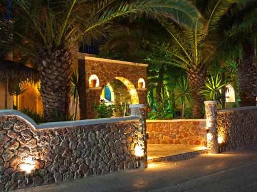 een resort met palmbomen en een stenen muur met verlichting bij Hotel Zeus in Kamari