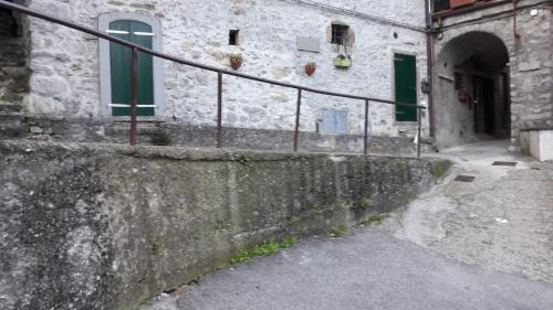 an old stone building with green windows and a sidewalk at Casa Quaratica in Riccò del Golfo di Spezia