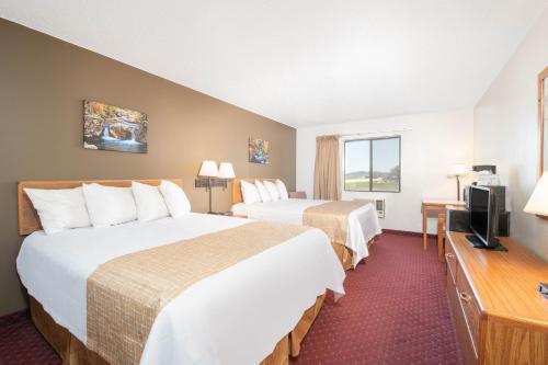 a hotel room with two beds and a flat screen tv at Travelodge by Wyndham Spearfish in Spearfish