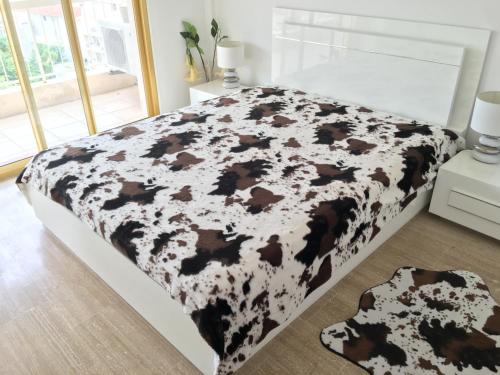 uma cama com um cobertor de vaca preto e branco em Cannes: Agréable 2 pièces vue mer panoramique em Cannes