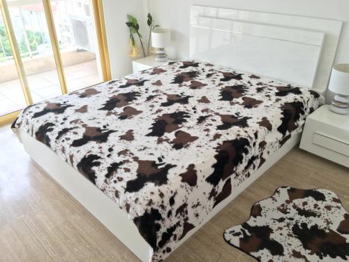 - un lit avec couverture de vache noire et blanche dans l'établissement Cannes: Agréable 2 pièces vue mer panoramique, à Cannes