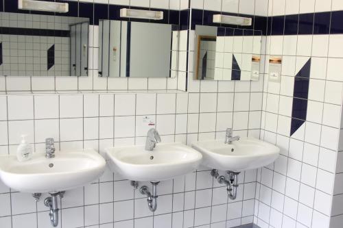 3 Waschbecken in einem weiß gefliesten Bad mit Spiegeln in der Unterkunft Erlebniscamping Lausitz - Campingplatz Ortrand / Camping Dresden in Ortrand