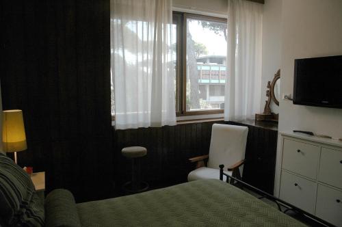 una camera con letto, finestra e sedia di Prestigioso appartamento Lagomare a Torre del Lago Puccini