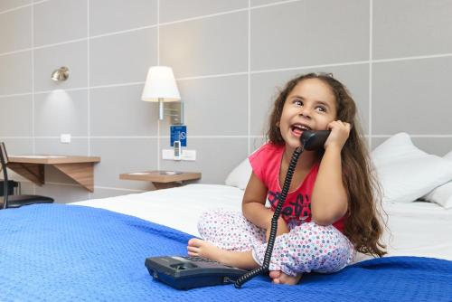 a little girl sitting on a bed talking on the phone at LP Equipetrol in Santa Cruz de la Sierra