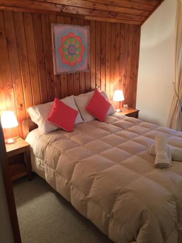 1 dormitorio con 1 cama grande con almohadas rojas en Hostería Bilbao, en Villarrica