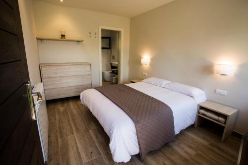 1 Schlafzimmer mit einem großen weißen Bett und einem Badezimmer in der Unterkunft Centro Medioambiental The Nest - Adults Only - Digital Detox in El Plano