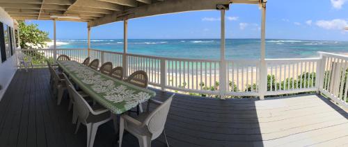a porch with a table and chairs on the beach at Mokulē'ia Beach Houses at Owen's Retreat in Waialua