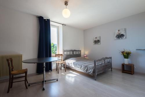 une chambre avec un lit, une table et une fenêtre dans l'établissement Gite La Janiat, à Montigny-sur-lʼAin
