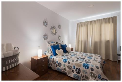 Un dormitorio con una cama con almohadas azules y una ventana en La Casita del Centro, en Vega de San Mateo