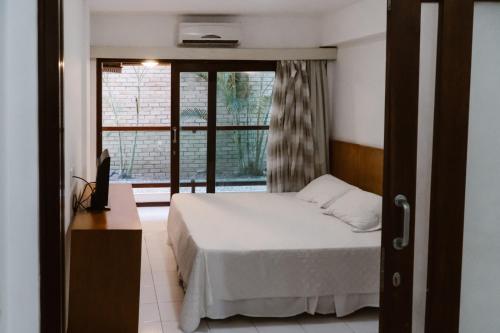 1 dormitorio con cama y ventana en Araçá Flat 106, en Natal
