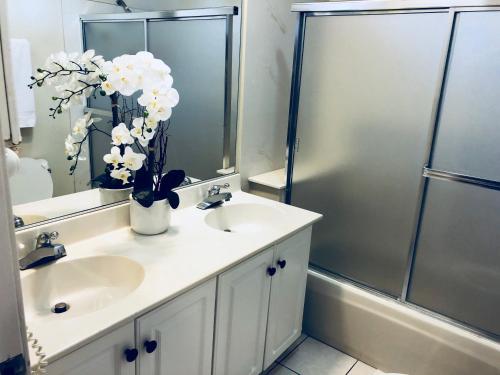a bathroom with a sink and a shower with white flowers at Victory Motel Inn near Universal & Hollywood in Glendale