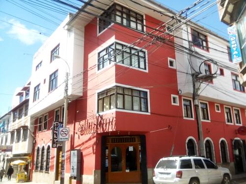 een rood-wit gebouw op de hoek van een straat bij Hostel Sillustani Inn Puno in Puno