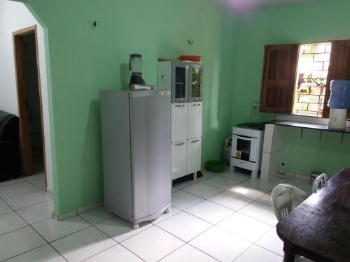 a kitchen with green walls and a white refrigerator at Casa de Veraneio in Salinópolis