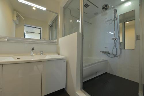 uma casa de banho com um lavatório, um chuveiro e uma banheira em Ocean Base Hagane em Izumo