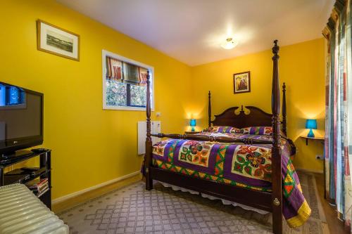 a bedroom with a bed and a tv and yellow walls at Cavendish Farm in Kaiapoi