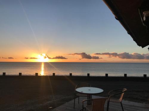 a sunset over the ocean with a table and chairs at El Reflejo Lodge Spa - Queilen - Chiloé in Queilén