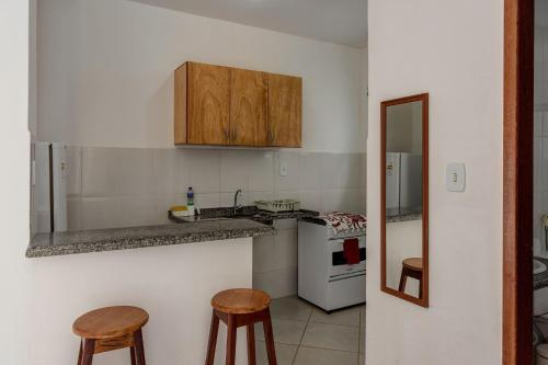 a kitchen with a stove and two stools at Pousada Lua e Mar in Ilhéus