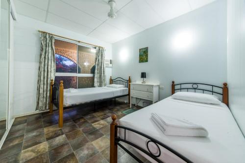 Hideaway Bay的住宿－Birdsong House- Dingo Beach，一间卧室设有两张床、一张桌子和一个窗口。