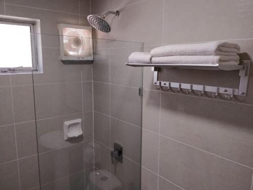 a bathroom with a shower with towels and a window at Yew Hotel in Miri