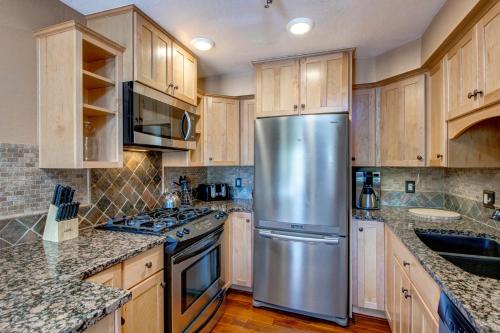 a kitchen with wooden cabinets and a stainless steel refrigerator at Quitting Time Condo in Park City