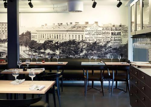 a restaurant with tables and chairs and a mural of the white house at Home Hotel Magasinet in Trelleborg