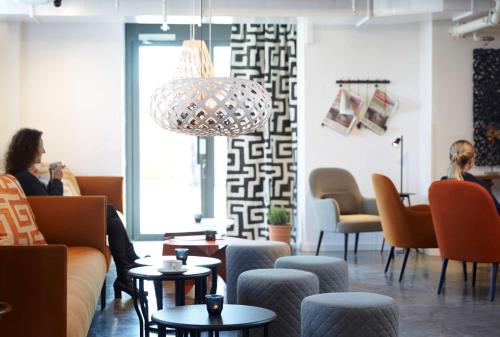 a lobby with couches and tables and people sitting at Home Hotel Magasinet in Trelleborg