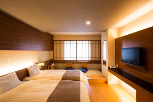 a hotel room with a bed and a flat screen tv at Choyo Tei in Kamikawa