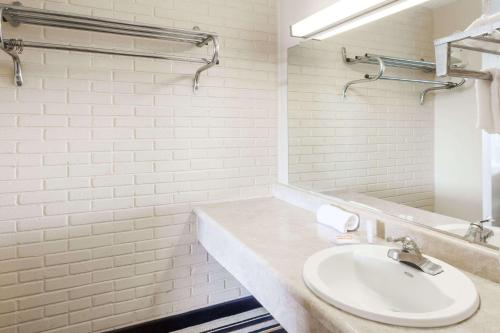 Baño blanco con lavabo y espejo en Days Inn by Wyndham Jackson, en Jackson