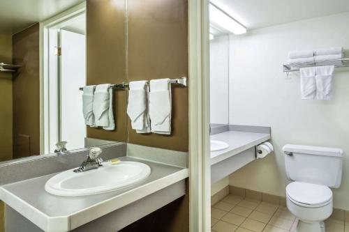 a bathroom with a sink and a toilet and a mirror at Days Inn & Suites by Wyndham Logan in Logan