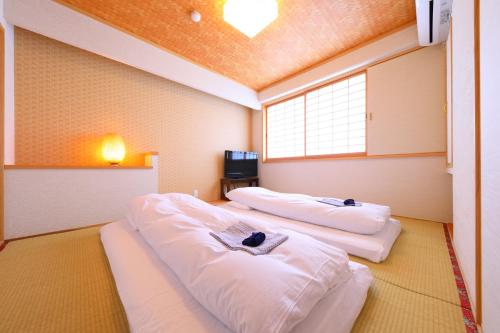2 camas blancas en una habitación con ventana en Business Hotel Star, en Beppu