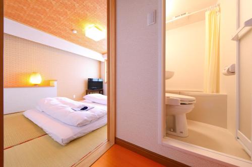 a bathroom with a bed and a toilet in a room at Business Hotel Star in Beppu