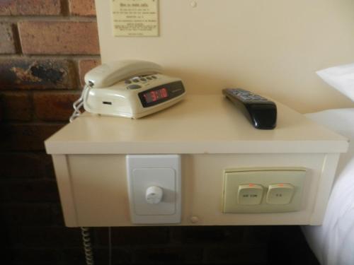 a table with a alarm clock and a telephone on it at Travellers Rest Motor Inn Swan Hill in Swan Hill