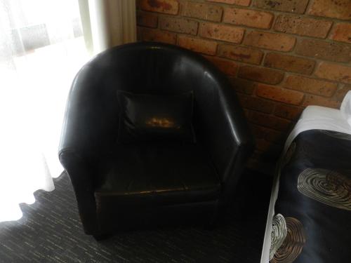 a black leather couch in a room with a brick wall at Travellers Rest Motor Inn Swan Hill in Swan Hill
