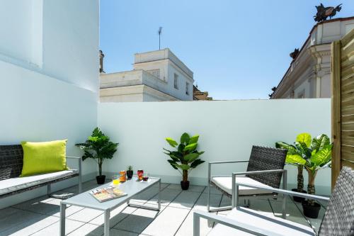 a balcony with chairs and a table on a building at La Puerta de Palacio - Adults Only in Seville