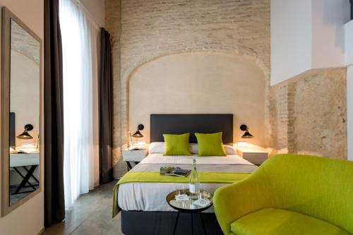 a bedroom with a bed and a green chair at La Puerta de Palacio - Adults Only in Seville
