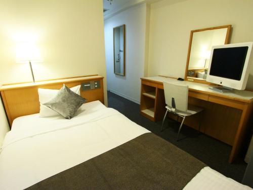 Habitación de hotel con cama y escritorio con ordenador en Hotel AreaOne Fukuyama, en Fukuyama