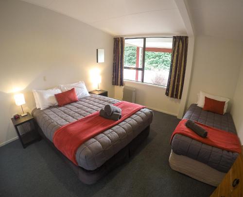 una camera d'albergo con due letti e una finestra di Mt Aspiring Holiday Park a Wanaka