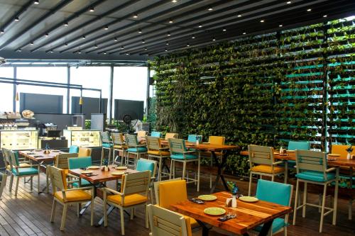 a restaurant with tables and chairs and a wall of wine bottles at The Empresa Hotel in Mumbai