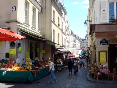 a street with people walking through a market with fruits and vegetables at Hôtel Monte Cristo in Paris