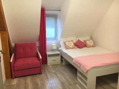 a bedroom with a bed and a red chair at Parkowy Kudowa in Kudowa-Zdrój
