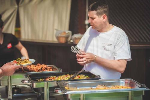 a man standing in front of a buffet with food at Mlyn Penzion & Wellness in Radvaň nad Dunajom