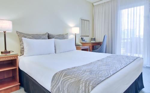a hotel room with a bed and a desk and a window at Soho Brisbane in Brisbane