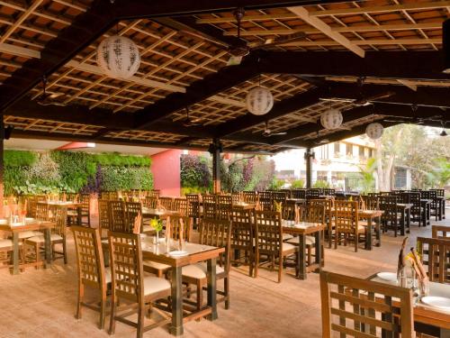 a restaurant with wooden tables and chairs and plants at Club Mahindra Saj Mahabaleshwar in Mahabaleshwar