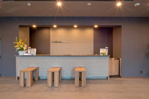a lobby with a counter with two wooden benches at Hotel Route Inn Takamatsu Yashima in Takamatsu