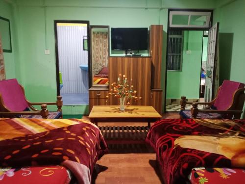 a room with two beds and a table and a tv at Zimba Happy Home Stay in Darjeeling