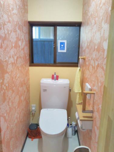a bathroom with a white toilet with a window at Guest House Hostel yukuru in Iiyama