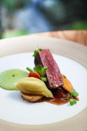 a plate of food with meat and fruit on it at Jambuluwuk Oceano Seminyak Hotel in Seminyak