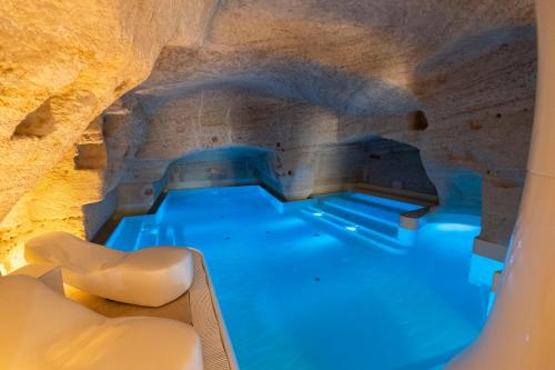 a pool in a cave with white chairs in the water at Aquatio Cave Luxury Hotel & SPA in Matera