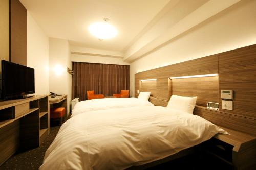 a hotel room with a large bed and a television at Dormy Inn Kagoshima in Kagoshima